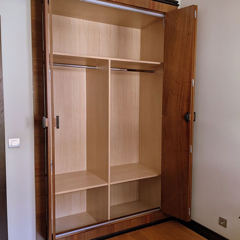 Armario de madera clara con puertas correderas plegables abierto