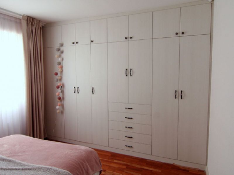 Armario en dormitorio de madera blanca y tiradores oscuros