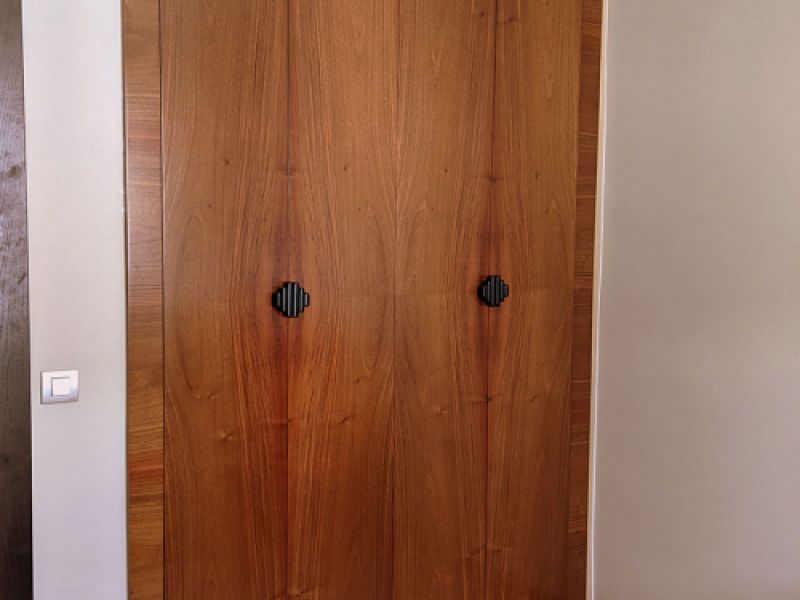 Armario de dos puertas de madera clara con tiradores negros